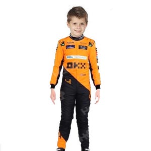 May include: A child wearing a racing suit. The suit is primarily orange with black accents on the legs and sleeves. The suit has sponsor logos and the number 4 on the leg. The child is smiling.