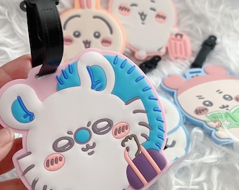 May include: A collection of silicone luggage tags featuring cartoon animal characters in pastel colors. Each tag has a black plastic strap and displays a unique design, including a white tiger with a purple suitcase and other round animal faces.