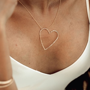 Image shows close up on model wearing our 14 karat yellow gold filled sweet heart necklace. Whether given as a Valentines gift for her or a token of self love, this adorable and elevated heart necklace will resonate with sweethearts around the world.