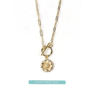 May include: A gold chain necklace with a sunflower charm and a toggle clasp.