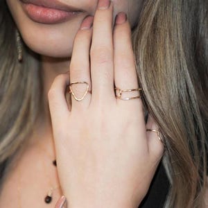 A close-up of a person's hand wearing multiple rings, with their fingers partially obscured by the rings.