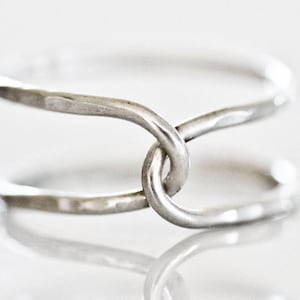 A silver ring with two intertwined rings forming a unique and intricate design.