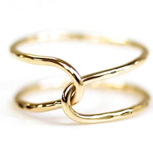 A close-up image of two gold rings with a twisted, intertwined design.