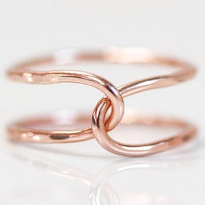 A close-up image of a delicate, intertwined ring with a copper-colored metal, creating a visually appealing and elegant design.