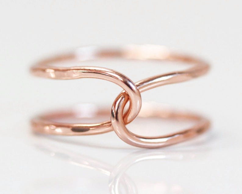 A close-up image of a delicate, intertwined ring with a copper-colored metal, creating a visually appealing and elegant design.