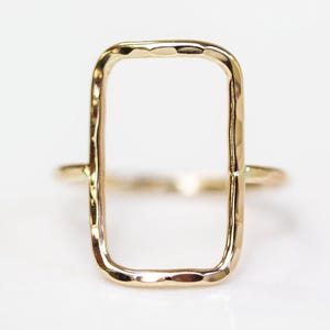 A simple, rectangular-shaped gold ring with a smooth, shiny finish.