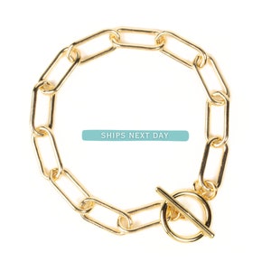 May include: A gold chain bracelet with a toggle clasp. The chain is made of oval links.