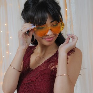 Image shows model wearing a few of our ultra thin 14 karat rose gold filled bangles. Each bangle bracelet is handcrafted from 14 karat Rose Gold Filled. Adding rose gold bangles to any ensemble or stacking bracelet set offers a treat for the senses.