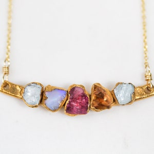 Image shows close up our our mothers birthstone necklace showcasing 5 unique birthstones. This personalized mom gift makes the best Christmas gifts. The raw stone necklace will be totally custom and unique with raw free form genuine birthstones.