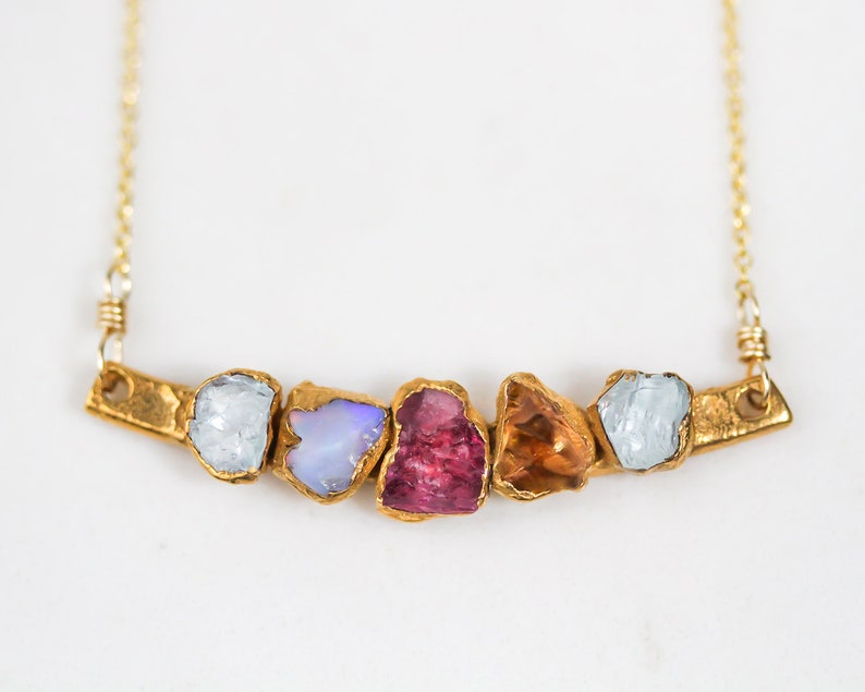 Image shows close up our our mothers birthstone necklace showcasing 5 unique birthstones. This personalized mom gift makes the best Christmas gifts. The raw stone necklace will be totally custom and unique with raw free form genuine birthstones.