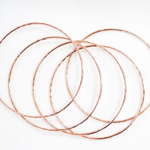 Image shows five of our 14 karat rose gold filled bangles. A hand hammered texture gives them their special sparkle. Made our of high quality rose gold filled material to stand the test of time. Can be worn for years without turning or tarnishing