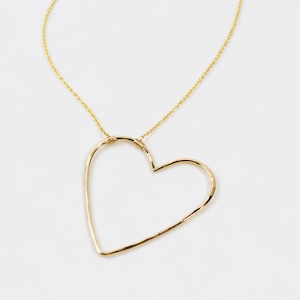 Close up shows the beautiful detail of our sweet heart necklace. Hand hammering creates facets in the metal that make it shine and delight. Expertly wire wrapped to our barely there chain for extra durability, this is the perfect gift for her.