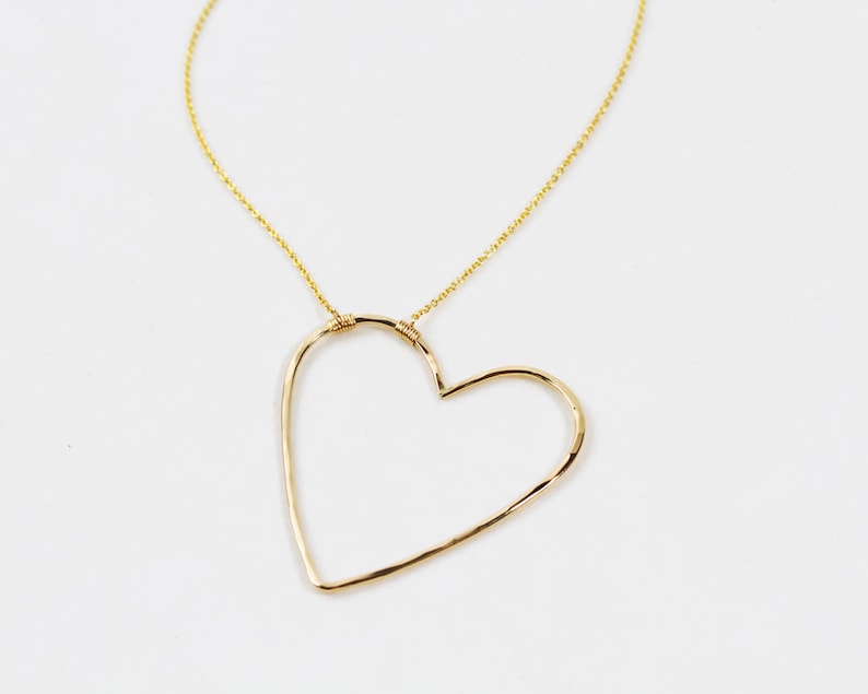 Close up shows the beautiful detail of our sweet heart necklace. Hand hammering creates facets in the metal that make it shine and delight. Expertly wire wrapped to our barely there chain for extra durability, this is the perfect gift for her.