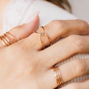 A close-up view of a person's hand wearing multiple gold rings on different fingers.