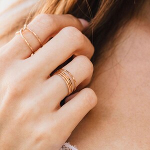 A close-up view of a person's hand wearing multiple rings on their fingers.