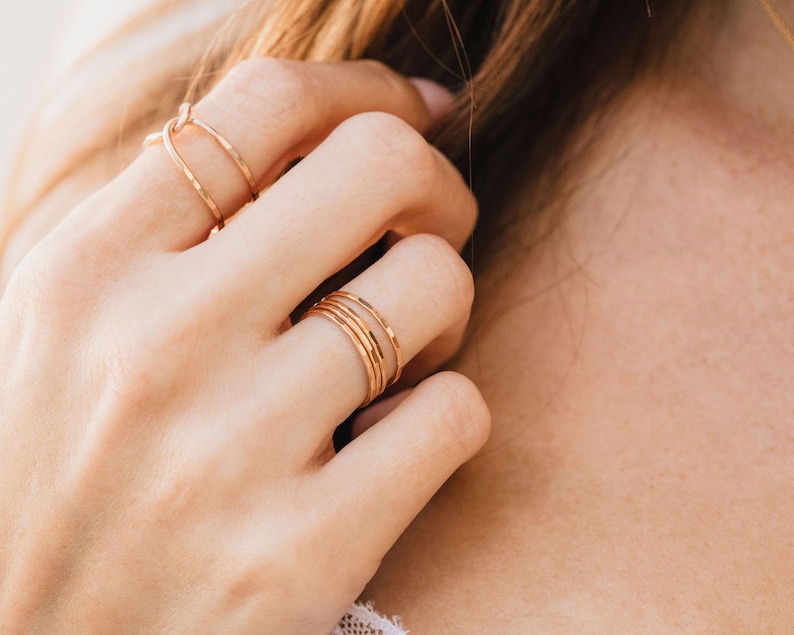 A close-up view of a person's hand wearing multiple rings on their fingers.