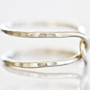 A close-up image of a silver ring with a twisted design.
