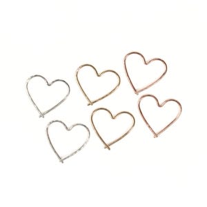 May include: Six wire heart-shaped ornaments in silver, gold, and rose gold. The hearts are arranged on a white background. These delicate, minimalist hearts are suitable for jewelry making or craft projects.