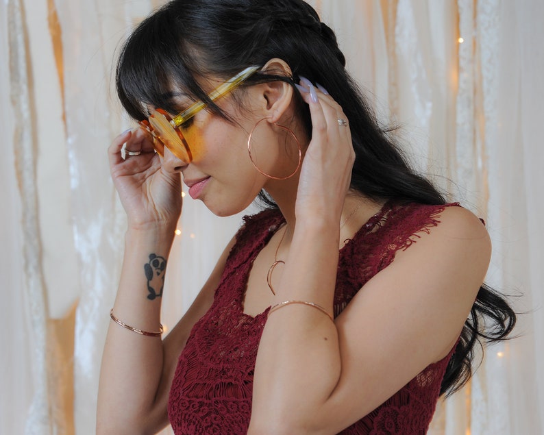 Image shows model wearing a few of our ultra thin 14 karat rose gold filled bangles. Each bangle bracelet is handcrafted from 14 karat Rose Gold Filled. Adding rose gold bangles to any ensemble or stacking bracelet set offers a treat for the senses.