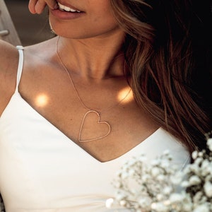 Image shows close up of our sweet heart necklace on model. The beautiful design will hold the heart asymmetrically while being worn. The Sweet heart Necklace captures the profound, flirty and exciting feeling of being sweet on someone. Perfect gift.