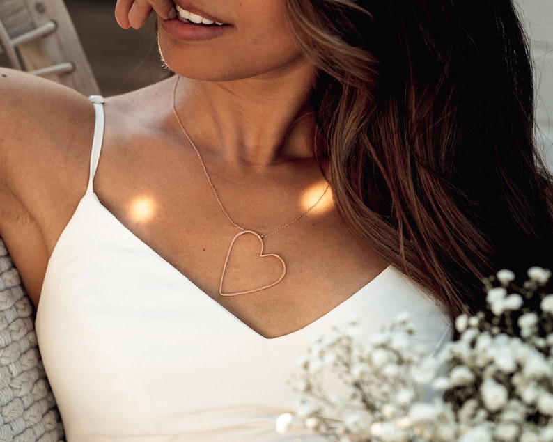 Image shows close up of our sweet heart necklace on model. The beautiful design will hold the heart asymmetrically while being worn. The Sweet heart Necklace captures the profound, flirty and exciting feeling of being sweet on someone. Perfect gift.