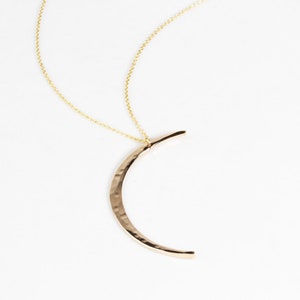 Close up shows the delicate and intentional texture of the moon in 14 karat yellow gold filled. Meant to mimic the look of the moon, the Mystic Moon Necklace elevates celestial jewelry and beams with handcrafted quality.