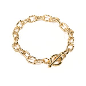 May include: A gold chain bracelet with a toggle clasp. The chain is made of oval links with a twisted rope design.