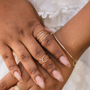 A close-up image of two hands wearing rings and bracelets.