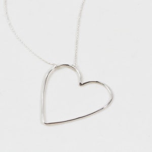 Close up shows our sweet heart necklace in .925 sterling silver. All handcrafted in house by our team of local artisans, each piece is made to order, just for you. Each heart receives a delicate hand hammer texture to cast off shine while being worn.