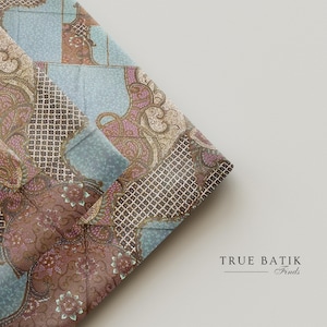 Op de afbeelding: Gevouwen stof met een gedetailleerd batikpatroon. Het ontwerp bevat een mix van kleuren, waaronder blauw, bruin en roze, met ingewikkelde bloemen- en geometrische elementen. De tekst "TRUE BATIK Finds" is zichtbaar.