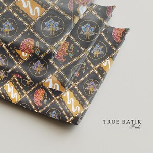 Könnte beinhalten: Gefalteter Stoff mit dunkelgrauem Hintergrund und einem sich wiederholenden Muster aus floralen und geometrischen Designs in Gold, Rot, Blau und Weiß. Der Stoff ist wahrscheinlich Batik, mit dem Text "TRUE BATIK Finds" unten rechts.