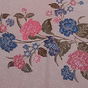 Op de afbeelding: Een bloemenpatroon met roze en blauwe bloemen, bruine bladeren en stelen. De bloemen zijn gedetailleerd en in volle bloei. De achtergrond is lichtroze met een gestippelde textuur.