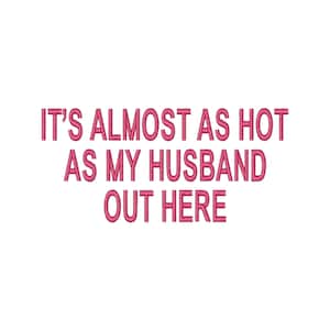 May include: Pink embroidered text on a white background reads: "IT'S ALMOST AS HOT AS MY HUSBAND OUT HERE."