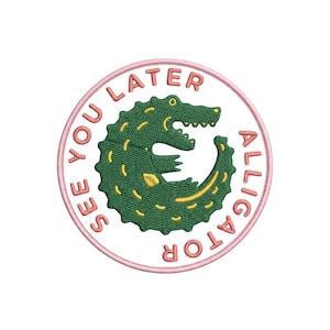May include: Embroidered patch with a green alligator and yellow details, surrounded by the pink text "SEE YOU LATER ALLIGATOR". The patch has a pink border and is on a white background.