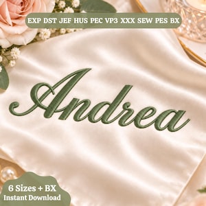 Könnte beinhalten: Eine Stickdatei mit dem Namen Andrea in einer dunkelgrünen Schreibschrift. Der Text ist auf einem glatten, cremefarbenen Satinstoff dargestellt. Das Bild enthält die Dateiformat-Bezeichnungen: EXP, DST, JEF, HUS, PEC, VP3, XXX, SEW, PES und BX.