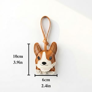 May include: A brown and white corgi-shaped keychain, 3.9 inches tall and 2.4 inches wide, with a leather loop. The keychain features a detailed design of a corgi's face and body.
