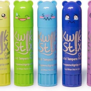 May include: A collection of colorful lip balms with bear-shaped caps and various facial expressions. Each balm has a different color, including gray, red, orange, yellow, green, blue, purple, pink, and brown. The text "Kwik Stix" is printed on each tube.