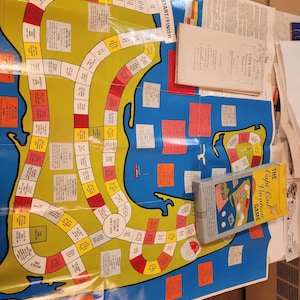 May include: A vintage board game titled "The Cape Cod Vacation Game" featuring a colorful map of Cape Cod. The game board is blue and yellow with various spaces and text. The game box is visible, along with instruction booklets.