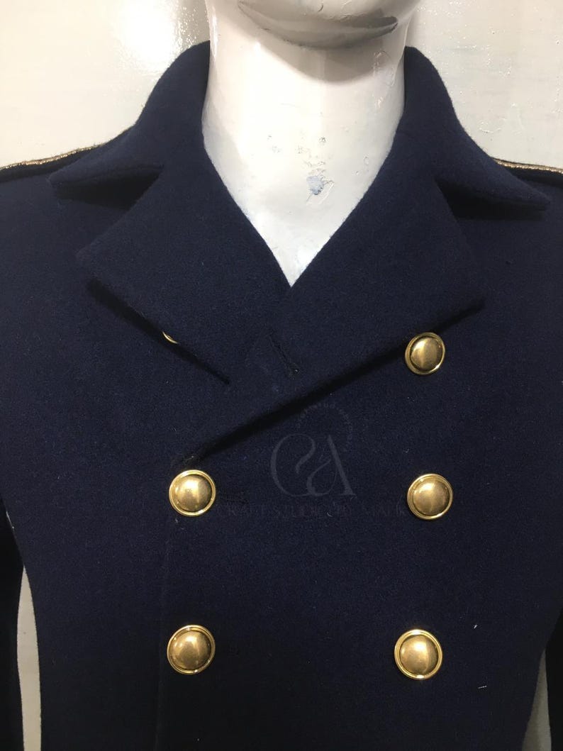 Peut inclure: Un manteau bleu marine &agrave; double boutonnage avec des boutons dor&eacute;s. Le manteau a un design classique avec un col crant&eacute; et une garniture dor&eacute;e sur les &eacute;paules. Les boutons sont grands et ronds, ajoutant une touche d'&eacute;l&eacute;gance.