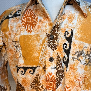 May include: A short-sleeved button-down shirt with a vibrant pattern. The shirt features a mix of orange, white, and brown geometric and abstract designs. The fabric has a textured appearance, and the shirt is displayed on a mannequin.
