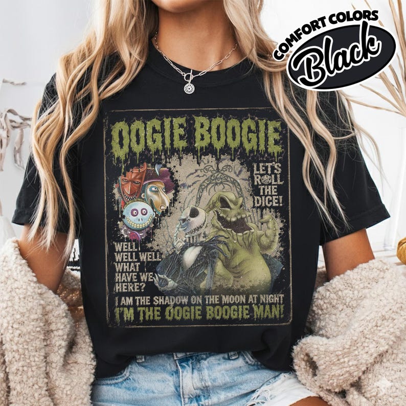May include: Black t-shirt featuring a graphic design with the text "Oogie Boogie" and various characters. The design includes the phrases "Let's Roll the Dice!" and "I'm the Oogie Boogie Man!" The shirt is labeled "Comfort Colors Black."