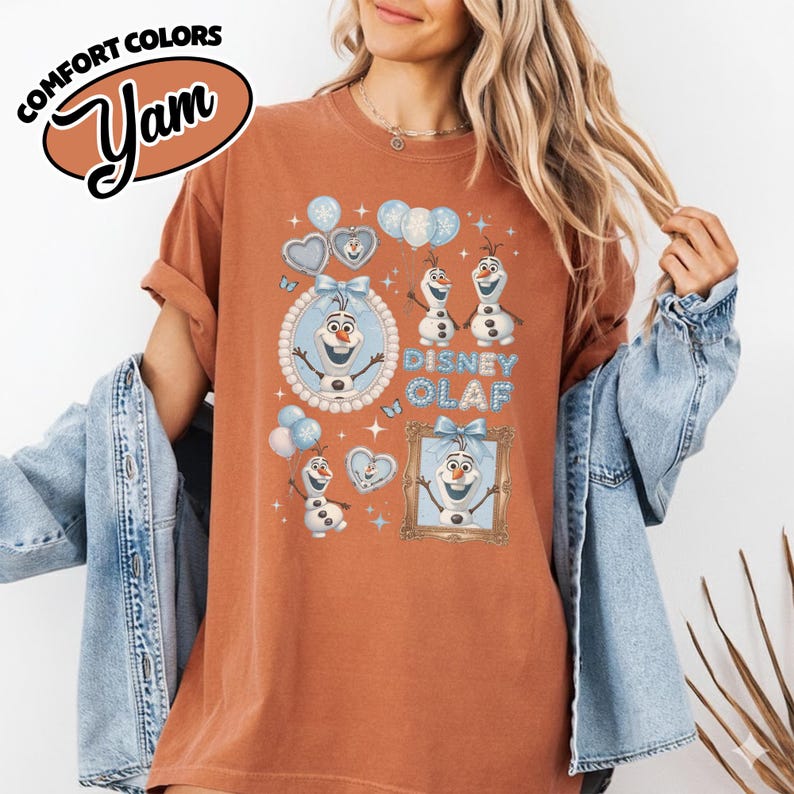 May include: A rust-colored t-shirt featuring the Disney character Olaf from Frozen. The design includes multiple images of Olaf, snowflakes, and the text "Disney Olaf". The shirt has short sleeves and a relaxed fit.
