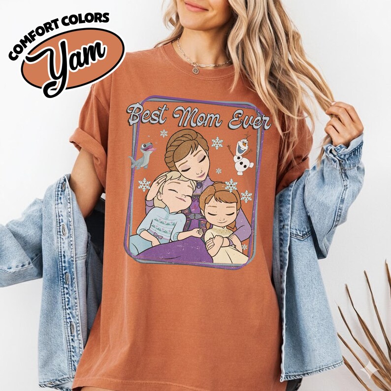 May include: A rust-colored t-shirt with the text "Best Mom Ever" and a cartoon illustration of a mother and two children. The shirt also features the Comfort Colors and Yam logos.