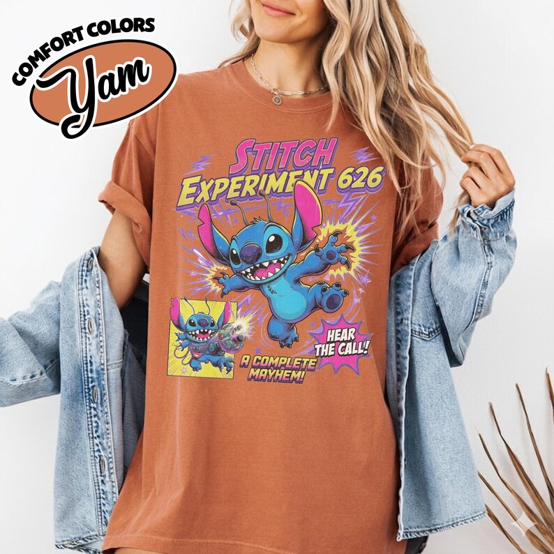 Może przedstawiać: T-shirt z kr&oacute;tkim rękawem w kolorze rdzawym z grafiką niebieskiej postaci Stitcha. Napis głosi STITCH EXPERIMENT 626, HEAR THE CALL! oraz A COMPLETE MAYHEM!. Małe okienko pokazuje Stitcha z pistoletem laserowym. Koszulka ma okrągły dekolt.