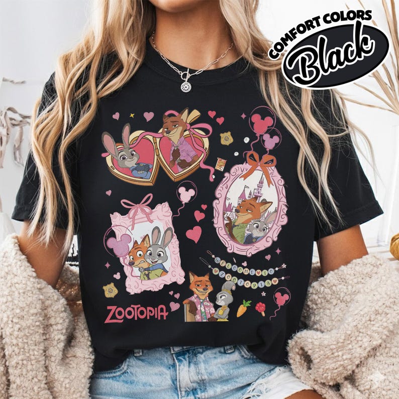 May include: A black t-shirt featuring a graphic print of Zootopia characters Judy Hopps and Nick Wilde. The design includes multiple framed illustrations, pink hearts, balloons, and the text Zootopia. A Comfort Colors Black label is visible.