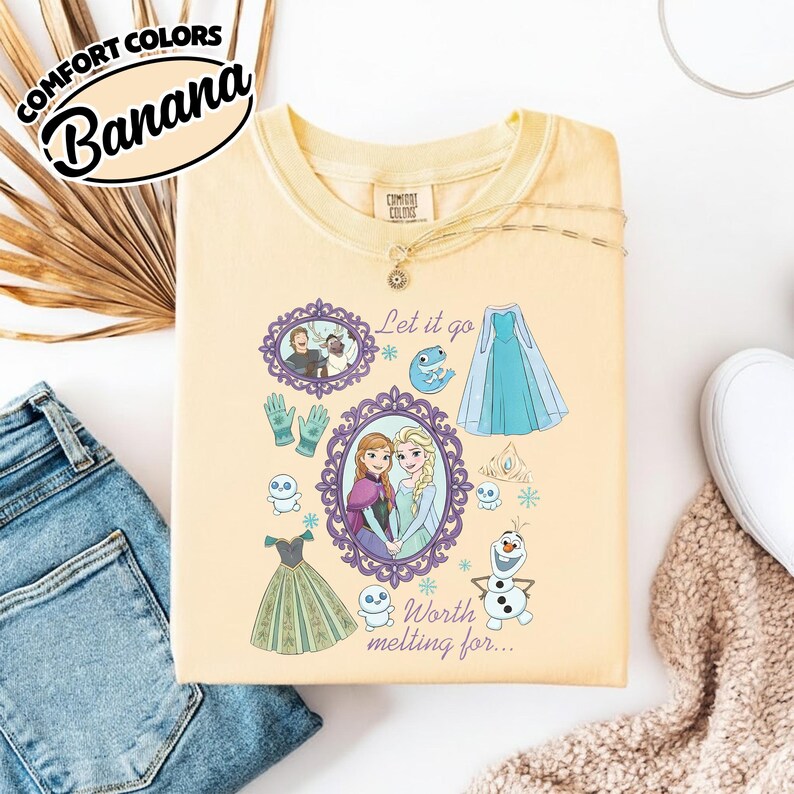 Op de afbeelding: Een lichtgeel sweatshirt met een grafisch ontwerp met personages en elementen uit de film Frozen. Het ontwerp bevat de tekst "Let it go" en "Worth melting for..." samen met afbeeldingen van Anna, Elsa, Olaf en andere personages.