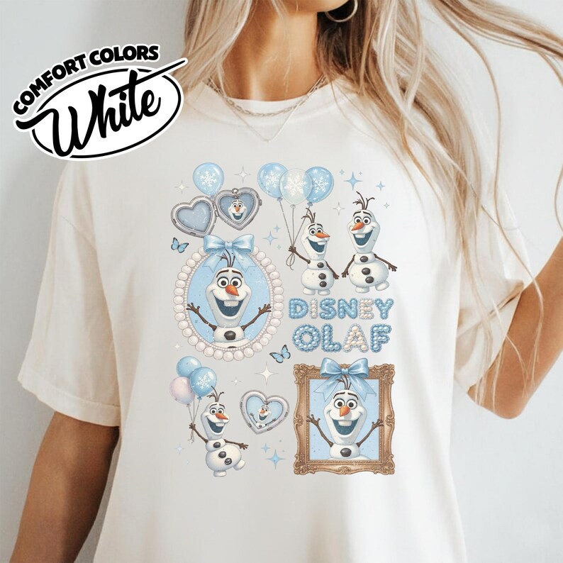 May include: White Comfort Colors t-shirt featuring a Disney Olaf design. The design includes Olaf the snowman, balloons, and the text "Disney Olaf" in blue. The shirt has a crew neck and short sleeves.