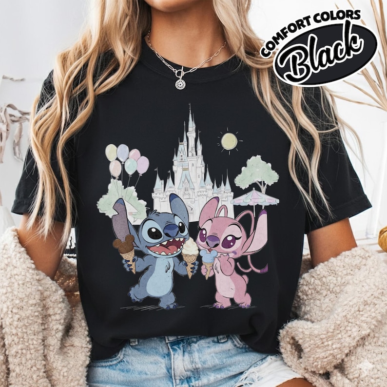 Puede incluir: Camiseta negra con una ilustraci&oacute;n de dibujos animados de Stitch y Angel sosteniendo conos de helado frente a un castillo. La camiseta tiene las palabras "COMFORT COLORS Black" en un dise&ntilde;o circular.