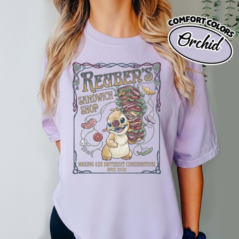 K&ouml;nnte beinhalten: Orchid Comfort Colors T-Shirt mit Cartoon-Grafik f&uuml;r "Renber's Sandwich Shop". Das Design beinhaltet eine l&auml;chelnde Figur, ein gro&szlig;es Sandwich und den Text "Making 625 Different Combinations Since 2001."