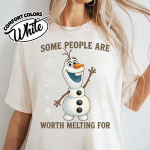 May include: White Comfort Colors t-shirt with the text "SOME PEOPLE ARE WORTH MELTING FOR" and a cartoon snowman character. The snowman has a carrot nose, twig arms, and three black buttons. Snowflake graphics are also present.